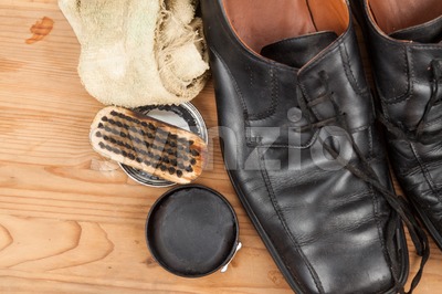 Shoe polish with brush, cloth and worn men shoes on wooden platform Stock Photo