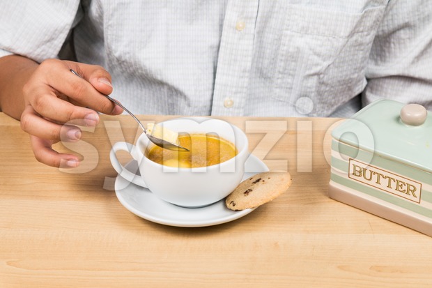 Person adding butter to coffee with milk, new diet that favor high amount of fat low carbo or ketogenic diet Stock Photo