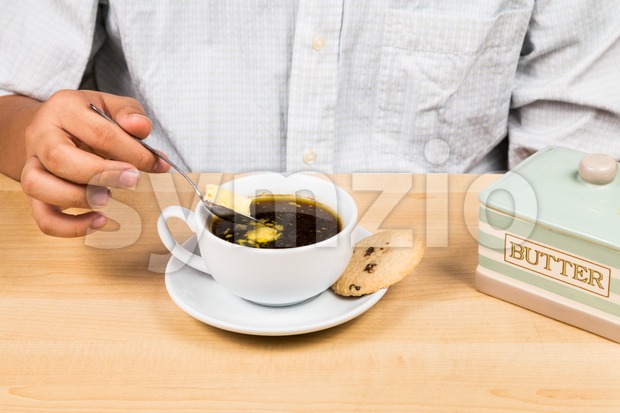 Person adding butter to back coffee, new diet that favor high amount of fat low carbo or ketogenic diet Stock Photo