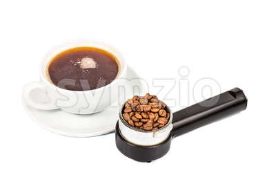 Coffee portafilter filled with coffee beans with a cup of freshly brewed espresso at the background Stock Photo