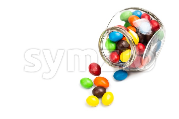 Transparent glass jar with colorful chocolate candies on white background Stock Photo