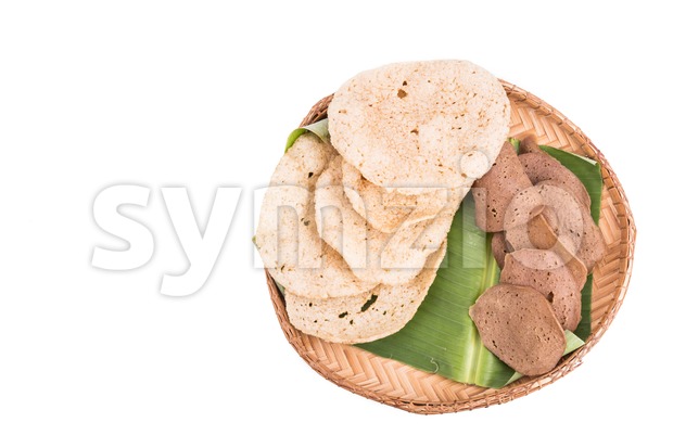 Freshly fried and dried raw fish crackers on rattan tray Stock Photo