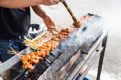 Vendor preparing chicken and beef barbecue satay on charcoal grille Stock Photo