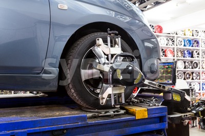 Closeup of tire clamped with aligner undergoing auto wheel alignment Stock Photo