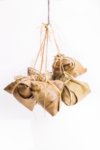 Bunch of Chinese rice dumpling tied hanging against white background Stock Photo