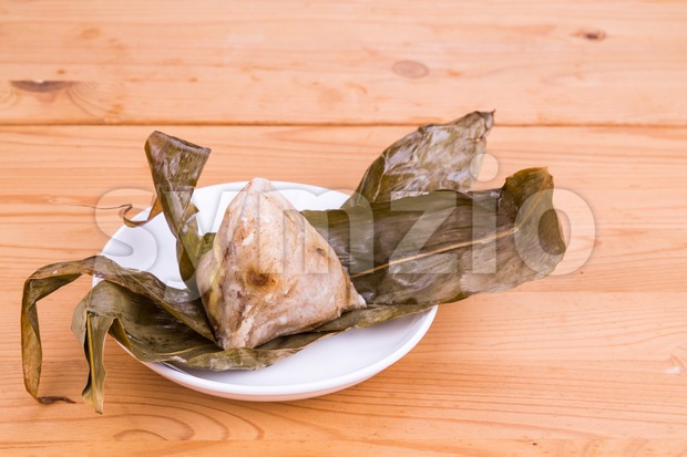Freshly prepared Chinese rice dumpling or zongzi unwrapped on plate Stock Photo