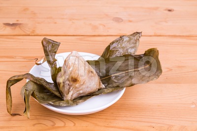 Freshly prepared Chinese rice dumpling or zongzi unwrapped on plate Stock Photo