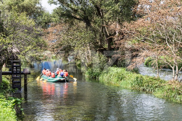 Group of people on raft peddling on serene scenic river Stock Photo