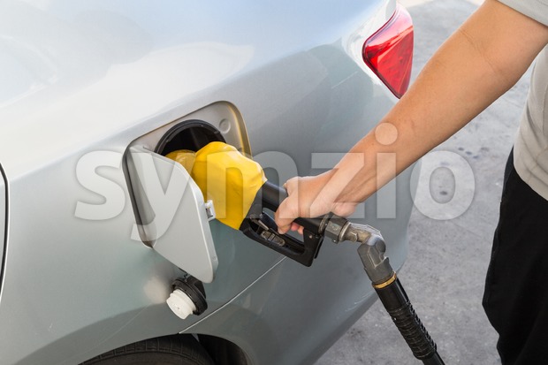 Hand with nozzle fueling unleaded gasoline into car Stock Photo