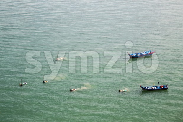 Fishermen harvesting shellfish and fish from the sea with net Stock Photo