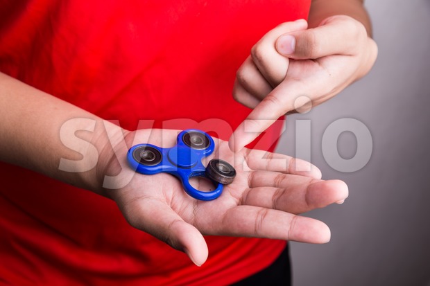 Person pointing dislodged weight from fidget spinner, dangerous for kids Stock Photo