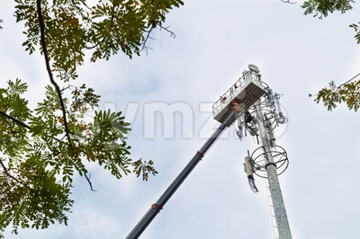 Two workers on crane installing mobile network communication antenna Stock Photo
