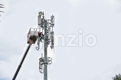 Two workers on crane installing mobile network communication antenna Stock Photo
