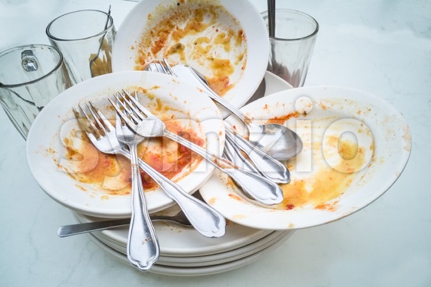 Pile of dirty oily plates, glass, fork spoons after meal Stock Photo