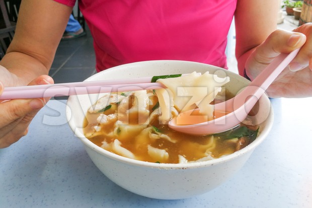 Person eating flat flour noodle soup or Pan Mee cuisine Stock Photo