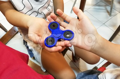 Underaged kids playing the fidget spinner. Maybe hazardous to kids. Stock Photo