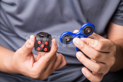 Person hand holding the fidget spinner and fidget cube Stock Photo