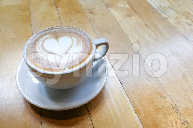 Cappuccino foam art with love heart shape on table Stock Photo