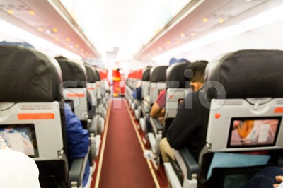 Defocused airplane cabin interior with seats and passengers Stock Photo
