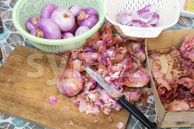 Onion skin being prepared peeled with knife, chopping board colander Stock Photo