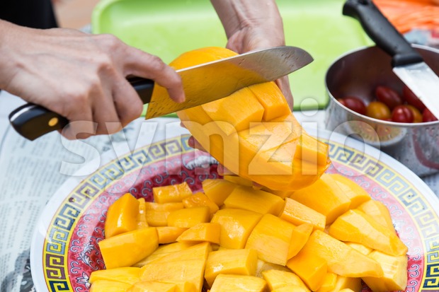 Hand holding knife cutting sweet delicious organic mango Stock Photo