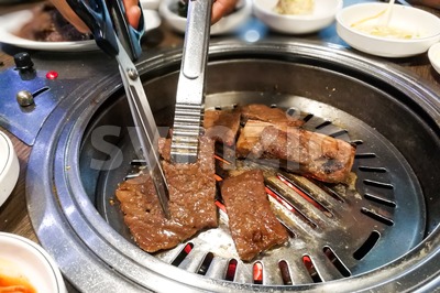 Person barbecue beef on bbq pit during korean meal set Stock Photo