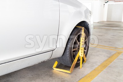 Car wheel clamped for illegal parking violation at car park Stock Photo
