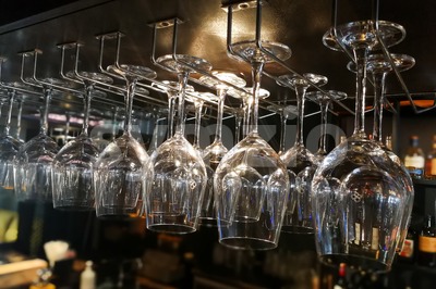 Empty wine glasses hanging on rack in bar Stock Photo