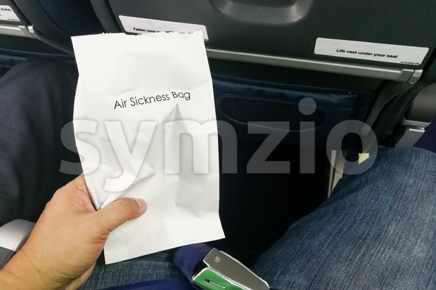 Airsick nauseous person holding the air sickness vomit bag Stock Photo