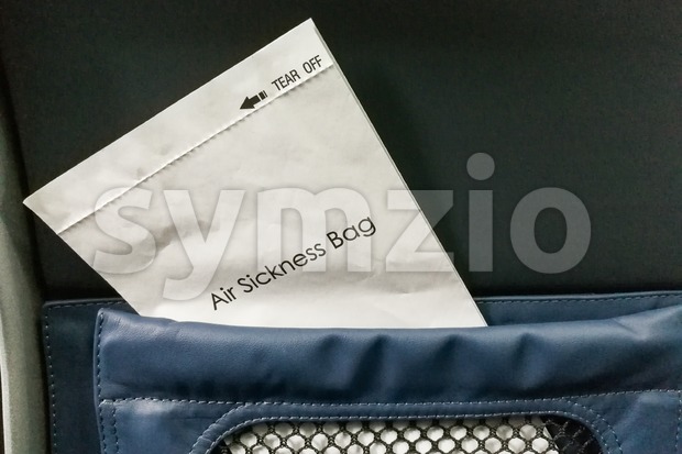 Air sickness bag tucked behind airplane seat pocket Stock Photo