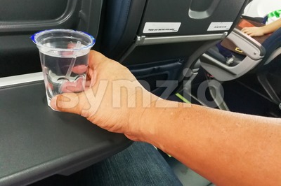 Hand holding disposable mineral water on table in air plane Stock Photo