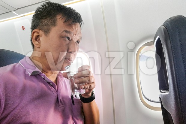 Person drinking water in airplane long haul flight to hydrate Stock Photo