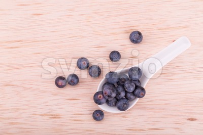 Organic blueberries scooped in spoon on wooden surface Stock Photo