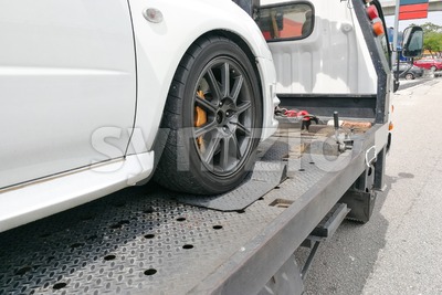 Car towed onto flatbed tow truck with hook and chain Stock Photo