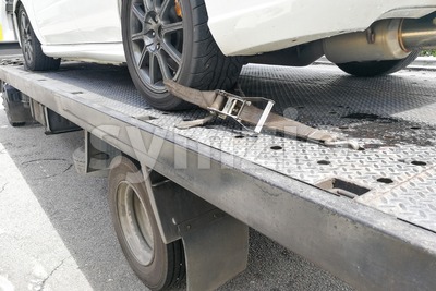 Car tire secured with safety belt on flatbed tow truck Stock Photo