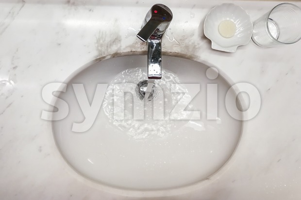 Modern hygienic wash basin with running water from tap faucet Stock Photo