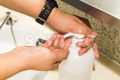 Closeup of person applying anti bacterial liquid onto hands Stock Photo