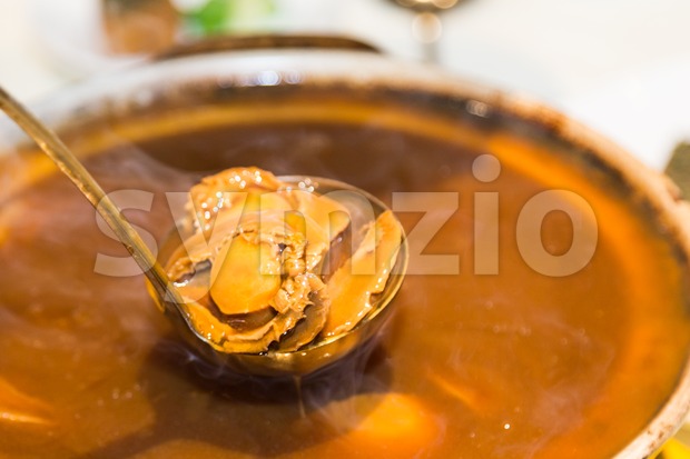 Closeup on delicious braised abalone scooped out from ceramic pot Stock Photo