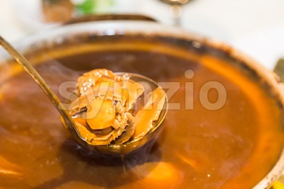 Closeup on delicious braised abalone scooped out from ceramic pot Stock Photo