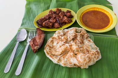 Roti prata on banana leaf with masala mutton, fish, curry Stock Photo