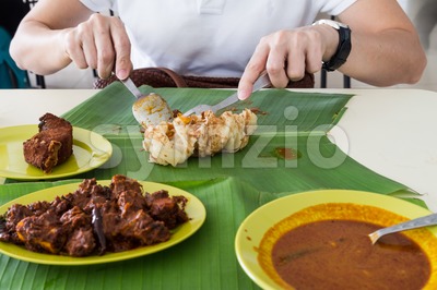 Person eating roti prata, masala mutton, fish on banana leaf Stock Photo