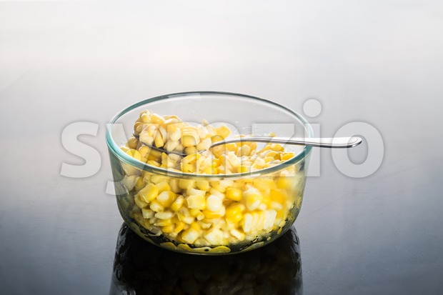 Corn kernels in transparent glass bowl  in dark reflective background Stock Photo