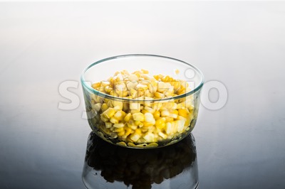 Corn kernels in transparent glass bowl  in dark reflective background Stock Photo